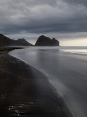 Cloudy view of Taitomo Rock at Piha Beach, Auckland, New Zealand.