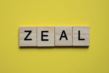 the gray word zeal of gray small wooden letters lies on a yellow table
