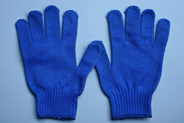 two new work gloves made of blue  fabric lie on a gray table