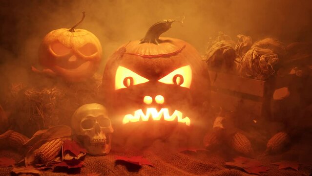Halloween pumpkins and harvest set in smoke and fog. Happy Halloween night with flickering pumpkins faces. Haunted scary night.