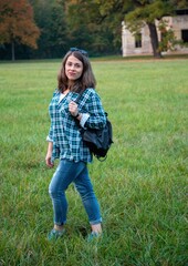 Fototapeta premium Adult woman posing in the autumn park on the grass field