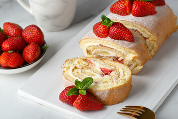 Sweet roll stuffed with strawberry and cream decorated with strawberries, powdered sugar and mint leaves