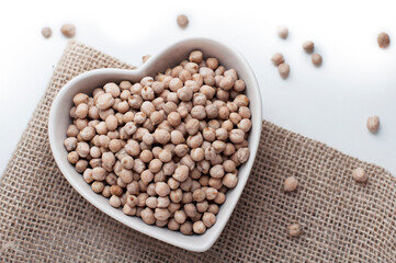 Chickpeas in a heart shaped bowl on canvas and white background