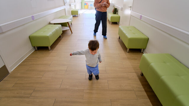 Happy Toddler Baby With A Woman Mother In The Clinic Waiting For A Doctor S Appointment. Mom With A Baby Boy In A Modern Hospital Before Receiving A Pediatrician. Kid Aged One Year And Three Months