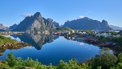Panoramic view on fishing village Reine, one of the most beautiful villages in Norway. Steep mountains at the background. The most beautiful hiking area in Lofoten. Summer vacation, tourist attraction - obrazy, fototapety, plakaty