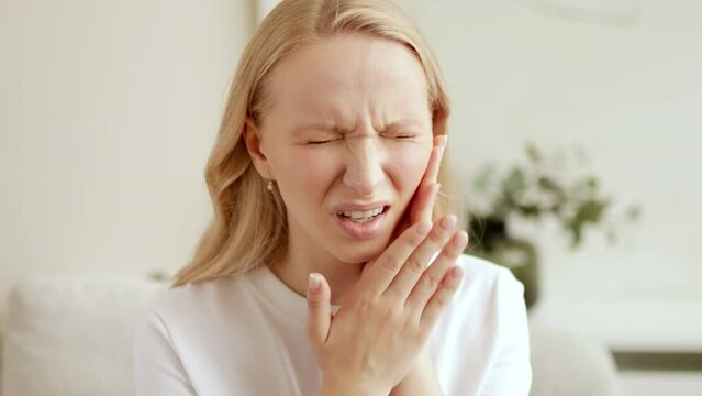 Woman with a toothache, touching her face. The concept of dental disease. Tooth pain due to caries