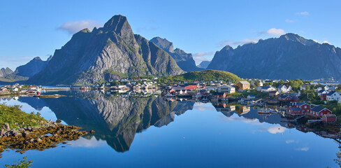 Panoramic view on fishing village Reine, one of the most beautiful villages in Norway. Steep mountains at the background. The most beautiful hiking area in Lofoten. Summer vacation, tourist attraction - obrazy, fototapety, plakaty