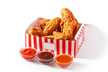 Crispy southern fried chicken in a red and white carry-out box with sauces on a white background...