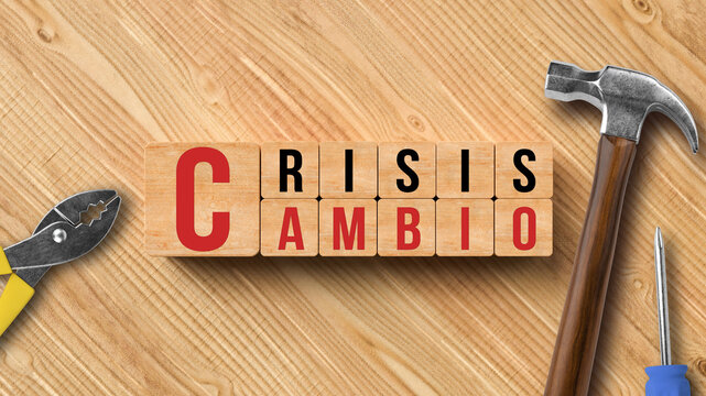cubes with the words CRISIS and CHANGE in Spanish with tools on wooden background