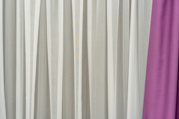 Obraz premium Delicate curtains in a new cozy apartment. Curtains cover the windows from the intrusive glances of neighbors and passers-by. The textile background is beige and pink.