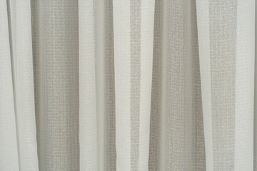 Obraz premium Delicate curtains in a new cozy apartment. Curtains cover the windows from the intrusive glances of neighbors and passers-by. The textile background is beige and pink.