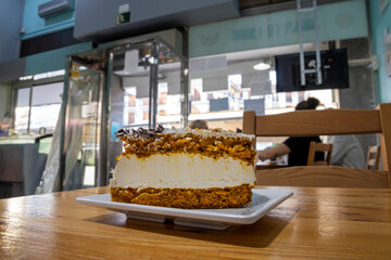 A piece of carrot and pumpkin cake, on a wooden table in a cafeteria. Healthy pastry concept.