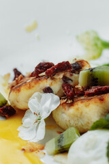 An ideal breakfast. Cottage cheese pancakes with caramel, almonds and cream sauce in a white plate. Ukrainian syrniki