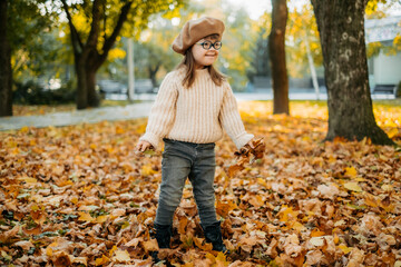 Happy child with a disability enjoying in the park on an autumn day tossing autumn leaves