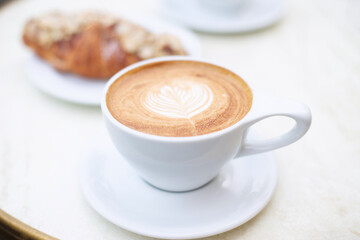 A cup of cappuccino and a croissant