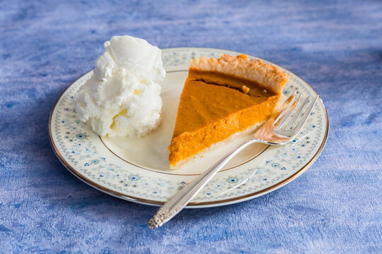 Slice of pumpkin pie with vanilla ice cream on a plate Thanksgiving background