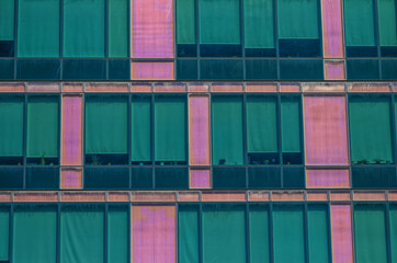 Fototapeta na wymiar Faded Pink and Teal Building Wall with Windows.