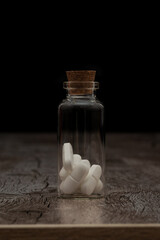 Pills in the glass phial on the dark background