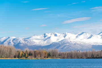 Snow cap Chugach Mountains and Downtown Anchorage buildings from Westchester Lagoon park