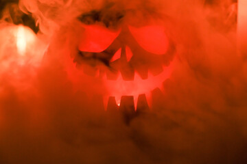 Fototapeta premium Halloween's holiday attributes. Halloween. carved pumpkin. candles . smoke . dark scene. pumpkin head silhouettes.