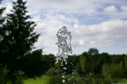 Shallow focus shot of splashing water with blur green trees in the park