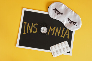 insomnia concert, the inscription insomnia on chalk board , alarm clock instead of letter o, sleep mask and pills