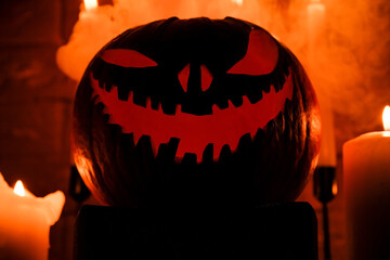 Fototapeta premium Halloween's holiday attributes. Halloween. carved pumpkin. candles . smoke . dark scene. pumpkin head silhouettes.