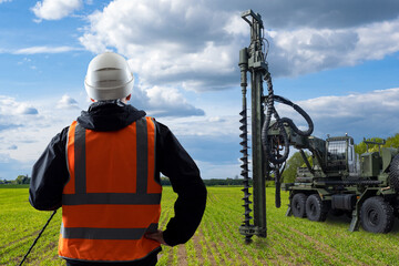 Well drilling during construction. Gaining access to water. Man is standing with his back to camera. Well drilling specialist. Drilling artesian well. Water treatment company worker in field