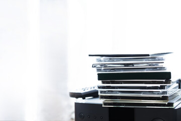 CD or music albums placed on a mini audio player by a window with incoming light.  Listening to music.