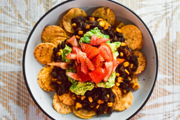 healthy plant-based food, vegan mexican bean nachos with corn chips guacamole and tomato salsa