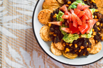 healthy plant-based food, vegan mexican bean nachos with corn chips guacamole and tomato salsa