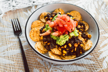 healthy plant-based food, vegan mexican bean nachos with corn chips guacamole and tomato salsa