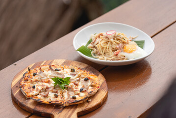 Pizza and Spaghetti carbonara with ham on wooden table