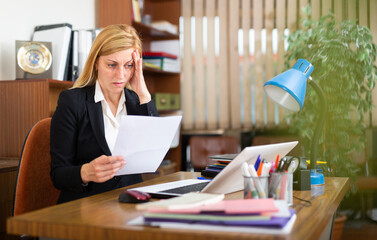 Portrait of upset female employee manager working with documents at working place