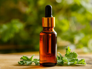 Geranium essential oil in dark glass bottle with fresh scented geranium leaves on old wooden board...
