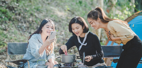 Young women cooking and use smartphone take photo on camping