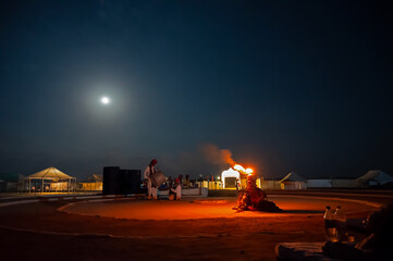 Rajasthani female dancer dancing with fire bowl on her head, dressed with cultural dress of Rajasthan, under full moon at night at Thar desert, Rajasthan, India.