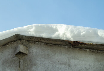 Snow drift on the metal roof of the garage after a snowfall. Close-up. Blue clear sky in the background