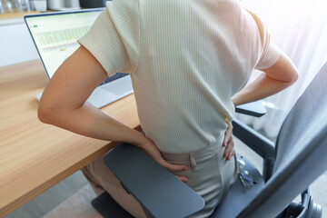 Woman having back body pain during work long time on workplace. due to Piriformis, Low Back, waist ache, lumbago, kidney, rheumatism and Spinal Compression. Office syndrome and Ergonomic concept - obrazy, fototapety, plakaty