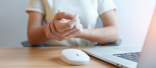 Woman having wrist pain when using mouse during working long time on workplace. De Quervain s...