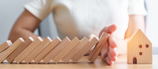 woman hand stop falling wood blocks and protect house model. Crisis, fall Business, Risk, Economic...