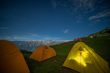 Night camping on mountain with sky and stars on green grass at Manali, India.