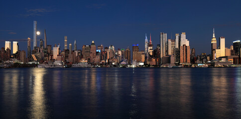 New York City skyline at night including the moon and nice reflection into Hudson River, USA