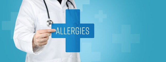 Allergies. Doctor holding blue cross with medical term on it.