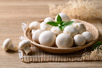 Fresh white champignon mushroom in basket on wooden background