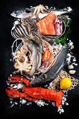Fresh fish and seafood assortment on black background, fish market. Healthy diet eating concept. Top view