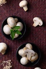Fresh white champignon mushroom in black bowl, Top view