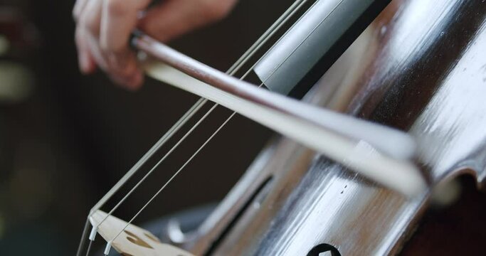 Female teacher playing contrabass string musical instrument with bow, Close up handheld shot