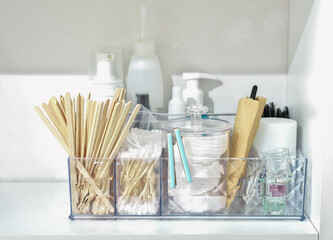 bathroom shelf with beauty care accessories, cotton swabs, disks, wooden sticks, cream bottles and lotion. face skin care and hygiene.