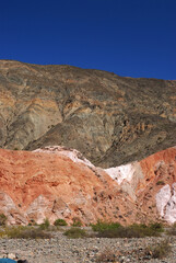 Altiplano. The arid desert and colorful mountains. View of the hiking path across the canyon. The orange sandstone and rocky formation part of Los Colorados in Purmamarca, Jujuy, Argentina.